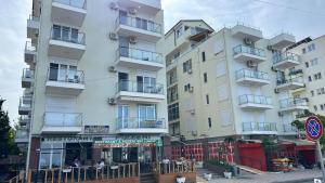 a tall white building with people sitting outside of it at Studio holidays in Shëngjin