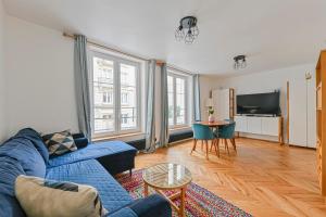 uma sala de estar com um sofá azul e uma televisão em PANTHEON em Paris