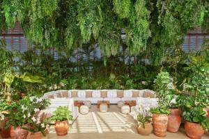 a white couch sitting in a garden with plants at The Riviera Maya EDITION at Kanai in Playa del Carmen +37 photos