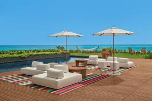 a patio with white chairs and tables and umbrellas at The Riviera Maya EDITION at Kanai in Playa del Carmen