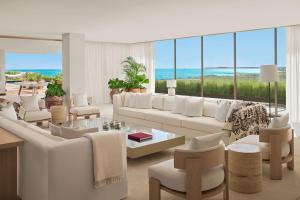 a living room with white furniture and a view of the ocean at The Riviera Maya EDITION at Kanai in Playa del Carmen