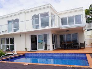 a house with a swimming pool in front of it at Luxury Palms in Paihia