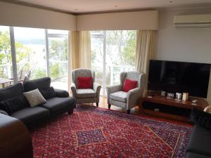 a living room with a couch and chairs and a television at Luxury Palms in Paihia