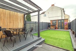 a patio with a table and chairs and a lawn at NEW Lily House by Truestays - 3 Bedroom House in Stoke-on-Trent in Newcastle under Lyme