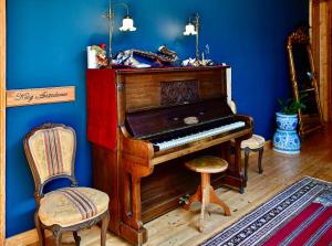 a wooden piano in a blue room with two chairs at VASILIKON Hotel 1888 the past is present in Kalamata