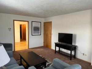 a living room with a couch and a table and a television at Entire apartment close to downtown - 2 queen beds in Springfield