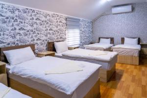 een kamer met 3 bedden en een muur met behang bij Muntazir Hostel in Yakkasaray
