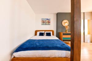 um quarto com uma cama com um cobertor azul em STUDIO PANTHEON em Paris