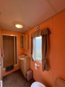 an orange bathroom with a sink and a toilet at Light and Airy 2 Bedroom Mobile Home in Aberystwyth