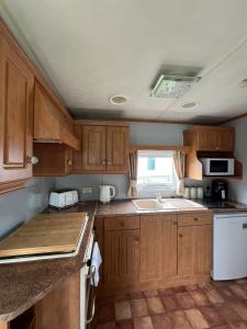 a small kitchen with wooden cabinets and a sink at Light and Airy 2 Bedroom Mobile Home in Aberystwyth