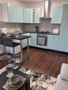 a kitchen with white cabinets and a table and a counter at Priory park view in Southend-on-Sea