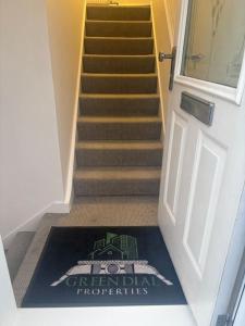 un tramo de escaleras con una alfombra de bienvenida delante de una puerta en Priory park view, en Southend-on-Sea