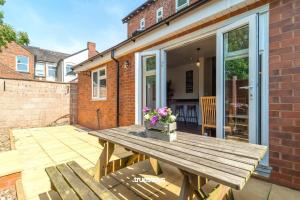 a wooden picnic table with flowers on a patio at NEW Oakhill House by Truestays - 5 Bedroom House in Stoke-on-Trent in Trent Vale