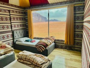 two beds in a room with a large window at desert splendor camp & jeep tours in Wadi Rum