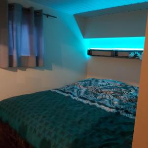 a bed in a bedroom with a blue light at La petite souche in Rochefort