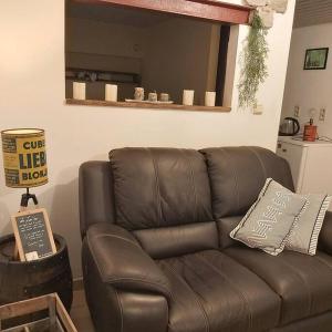 a brown leather couch in a living room with a sign at La petite souche in Rochefort