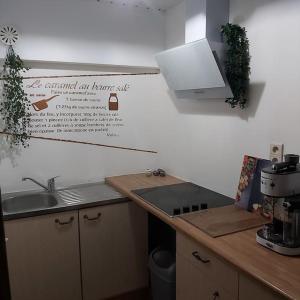 a kitchen with a sink and a sign on the wall at La petite souche in Rochefort