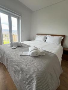 Una cama blanca con toallas y una ventana. en O Pôr do Sol do Gerês, en Paradela