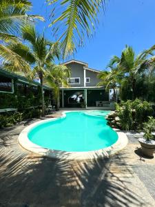 una piscina frente a una casa con palmeras en CHICO DINA POUSADA, en Amontada