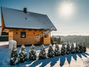 uma cabana com árvores cobertas de neve à sua frente em Tatra Village em PyzÃ³wka