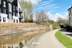 un canal dans une ville avec des bâtiments et un mur de briques dans l'établissement Bridgewater House by Truestays - NEW 3 Bedroom House in Stoke-on-Trent, à Etruria