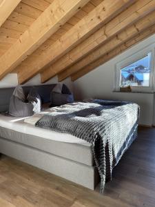 a large bed in a room with a wooden ceiling at Haus Alpgaustraße - Ferienhäuser Alpenglück in Oberstdorf