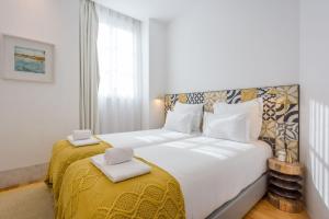 - une chambre avec un grand lit et une couverture jaune dans l'établissement Be Local - Historic house of Santo André in Alfama - Lisbon, à Lisbonne