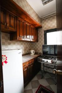 eine Küche mit Holzschränken und einem weißen Kühlschrank in der Unterkunft Amazing Flat 9 mins to Airport at Heliopolis in Kairo