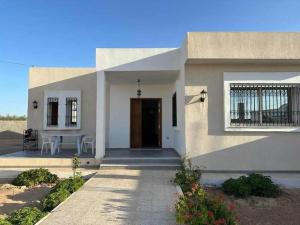 a white house with a front door and a table at Villa S+3 Houmet Souk Djerba in Houmt Souk