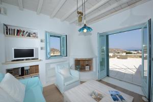 - un salon avec une télévision, un canapé et une chaise dans l'établissement Villa Danelina by Whitelist Mykonos, à Ornos