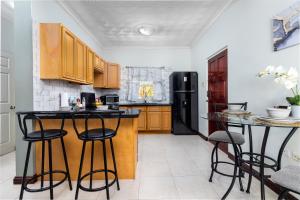 a kitchen with a black refrigerator and two bar stools at Cozy, upscale apartment centrally located in Kgn 6 in Kingston