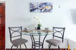 a glass table with two chairs and a vase on it at Cozy, upscale apartment centrally located in Kgn 6 in Kingston