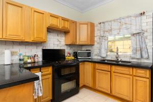 una cocina con armarios de madera y electrodomésticos negros en Cozy, upscale apartment centrally located in Kgn 6, en Kingston