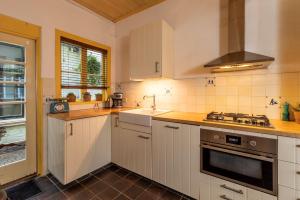a kitchen with white cabinets and a sink and a stove at Posthuisje Zandvoort in Zandvoort
