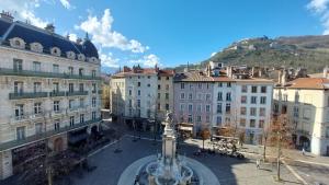 Une ville avec des bâtiments et une statue au milieu dans l'établissement Hyper-centre de Grenoble, ambiance tropicale, wifi fibre, à Grenoble