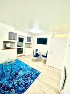 a living room with a blue rug and a table at Cozy One Bedroom Apartment With Free Car Park In London in London