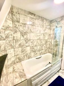 a bathroom with a tub and a glass shower at Cozy One Bedroom Apartment With Free Car Park In London in London