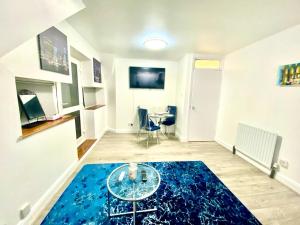 a living room with a glass table on a blue rug at Cozy One Bedroom Apartment With Free Car Park In London in London