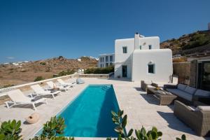 a swimming pool with lounge chairs and a villa at Villa Danelina by Whitelist Mykonos in Ornos