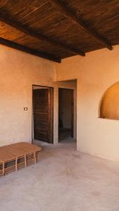 a room with a wooden bench and a wall at Stamps Siwa Oasis in Siwa