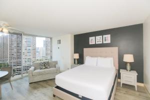 a bedroom with a large white bed and a chair at Ilikai Marina 1781 City View Studio in Honolulu