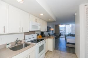 a kitchen with white cabinets and a sink at Ilikai Marina 1781 City View Studio in Honolulu