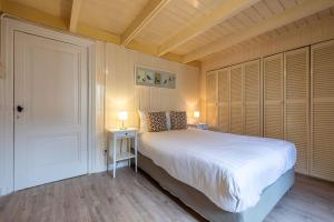 a bedroom with a bed and two lamps and a door at Posthuisje Zandvoort in Zandvoort