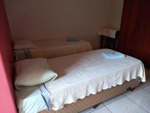 twee bedden in een kleine kamer met bij Ap duplo econômico, com banheiro, sem café ou TV no Espaço Verona in Fazenda Rio Grande