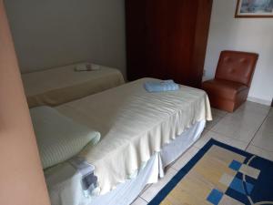 een kamer met 2 bedden en een stoel bij Ap duplo econômico, com banheiro, sem café ou TV no Espaço Verona in Fazenda Rio Grande