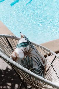 a pillow sitting on a chair next to a swimming pool at Hôtel Les Fougères in Hossegor