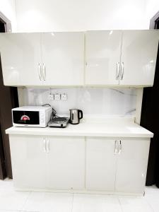 cocina con armarios blancos, tostadora y microondas en Luxury Apartment 21 en Riad