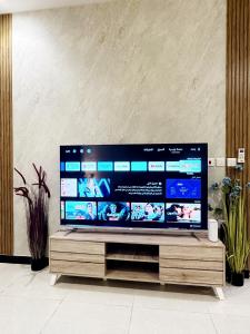 duży telewizor z płaskim ekranem siedzący na drewnianym stojaku w obiekcie Luxury Apartment 21 w Rijadzie
