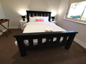 a bedroom with a large black bed with two lamps at The Winemakers Quarters in Tanunda