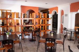 un restaurante con mesas, sillas y estanterías con jarrones en Estanza Hotel & Suites en Morelia